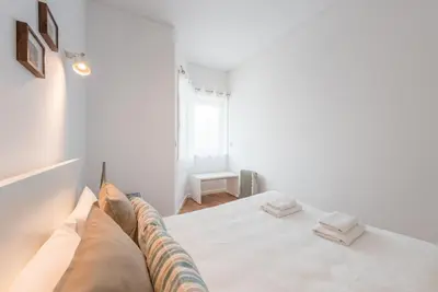 a white bedroom with a bed with white sheets and pillows at GuestReady - Cedofeita Cradle in Porto