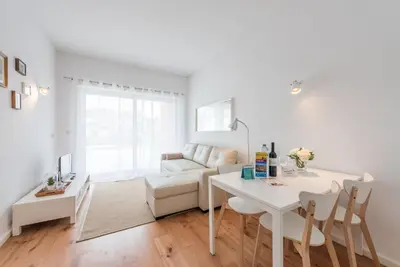a white living room with a table and a couch at GuestReady - Cedofeita Cradle in Porto