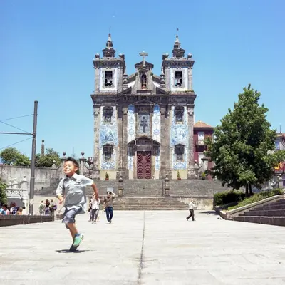 a young boy running in front of an old building at Porto Insight Apartments- with balcony in Porto