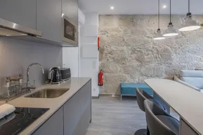 a kitchen with a sink and a counter with chairs at Ribeira Apartments Baixa in Porto