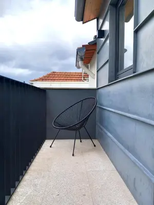 a chair sitting on a patio next to a building at Fontinha House in Porto