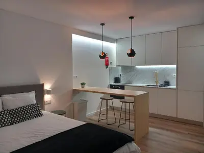 a bedroom with a bed and a desk and a kitchen at Fontinha House in Porto