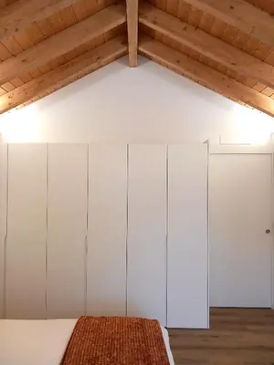 a bedroom with white wardrobes and a wooden ceiling at Fontinha House in Porto