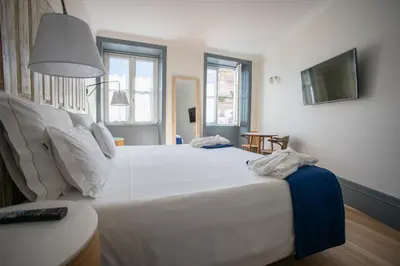 a bedroom with a large white bed and a television at Porto A.S. 1829 Hotel in Porto