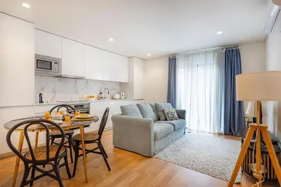 a living room with a blue couch and a kitchen at Porto Living | 1BR Flat with AC in Porto