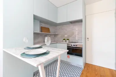 a white kitchen with a table with wine glasses at Formosa Studios by Upperground in Porto