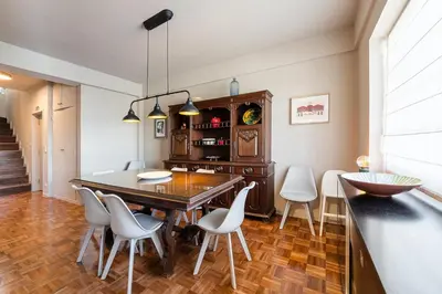a dining room with a wooden table and white chairs at GuestReady - A charming duplex home near Boavista in Porto