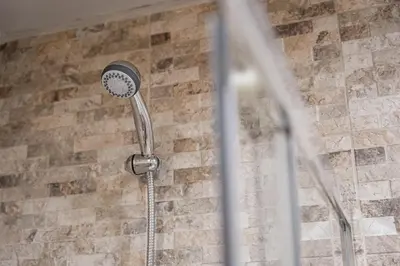 a shower with a shower head on a brick wall at GuestReady - A charming duplex home near Boavista in Porto