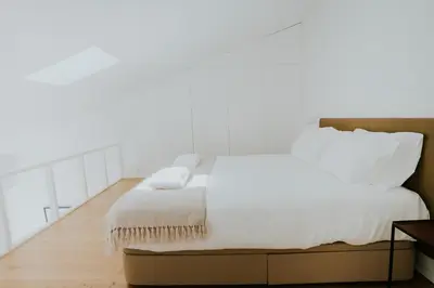 a bed with white sheets and pillows on it at VIVA Formosa Lofts in Porto