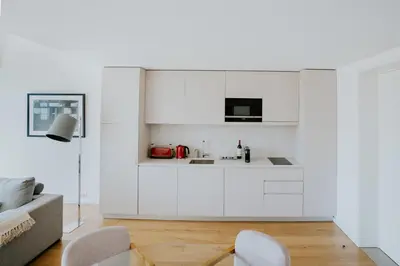 a white kitchen with white cabinets and a couch at VIVA Formosa Lofts in Porto
