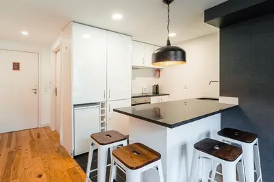 a kitchen with white cabinets and a counter with stools at GuestReady - Charming Mezzanine near Porto in Vila Nova de Gaia
