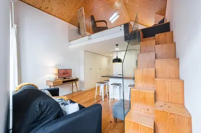 a living room with a black couch and a kitchen at GuestReady - Charming Mezzanine near Porto in Vila Nova de Gaia