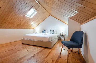 a bedroom with a bed and a chair in a attic at GuestReady - Charming Mezzanine near Porto in Vila Nova de Gaia