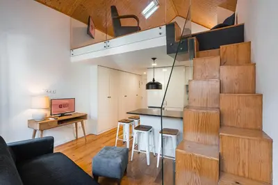 a living room with a staircase leading up to a loft at GuestReady - Charming Mezzanine near Porto in Vila Nova de Gaia