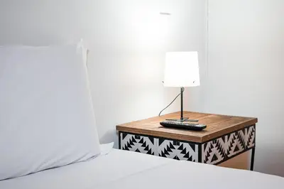 a lamp on a night stand next to a bed at GuestReady - Charming Mezzanine near Porto in Vila Nova de Gaia