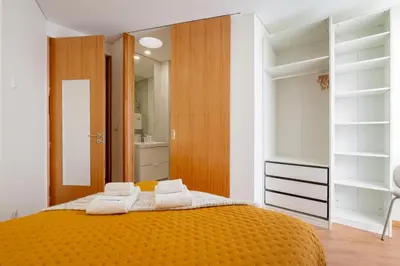 a bedroom with an orange bed with towels on it at Host Wise - Bright and Cozy House with Dom Luís Bridge View in Porto