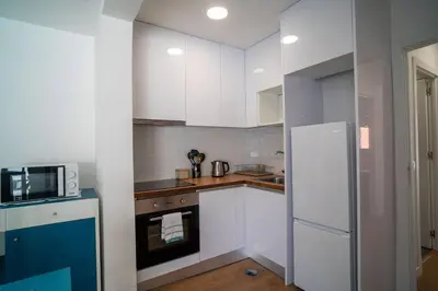 a kitchen with white cabinets and a white refrigerator at Casa da fonte in Vila Nova de Gaia