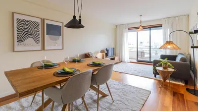 a living room with a wooden table and chairs at Apartamento com varanda e garagem in Porto