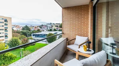a balcony with two chairs and a view of a city at Apartamento com varanda e garagem in Porto