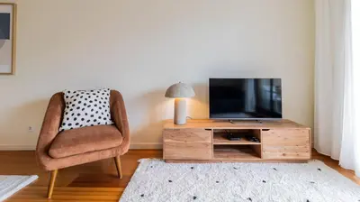 a living room with a chair and a television at Apartamento com varanda e garagem in Porto