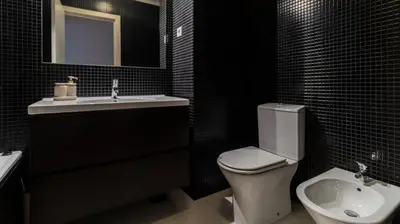 a bathroom with a toilet and a sink and a mirror at Apartamento com varanda e garagem in Porto
