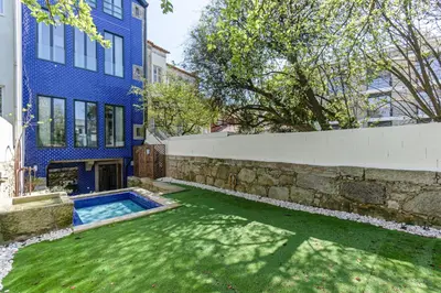 a blue building with a swimming pool next to a yard at GuestReady - Alegria Guesthouse in Porto