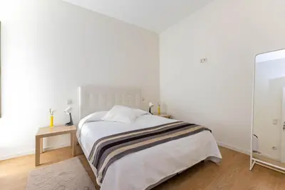 a white bedroom with a bed and a mirror at D&S - Antas House in Porto