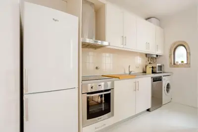 a kitchen with white cabinets and a refrigerator at Sunny Priorado Vintage studio with balcony in Porto