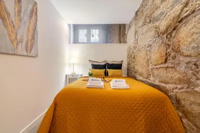 a bedroom with a yellow bed with a stone wall at Host Wise - Modern Comfy Flat in Porto
