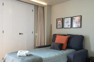a bedroom with a bed and a blue couch at Host Wise - Modern Design Duplex w Balcony in Porto