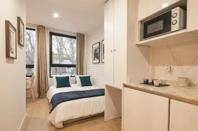 a bedroom with a bed and a kitchen with a window at Marquês Oporto Apartment in Porto