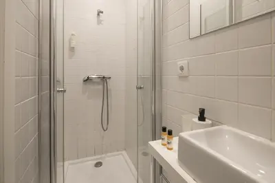 a white bathroom with a shower and a sink at Marquês Oporto Apartment in Porto