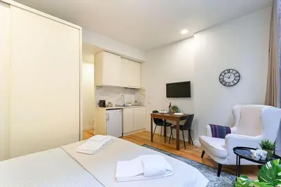 a room with a bed and a table and a kitchen at Santa Catarina Oporto City Center in Porto