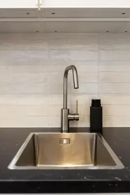 a stainless steel kitchen sink with a faucet at Bright apartment with garden in Porto