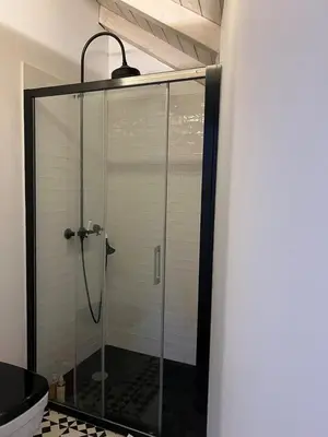 a shower with a glass door in a bathroom at Get bindings and books on duplex in Porto
