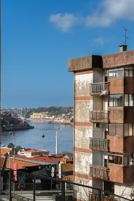 a tall building with a view of a river at Host Wise - Large Colourful Flats - Ace Location in Vila Nova de Gaia