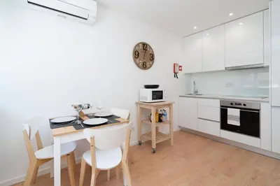 a kitchen with white cabinets and a table with chairs at Host Wise - Sweet Sunny Flat with Balcony in Vila Nova de Gaia
