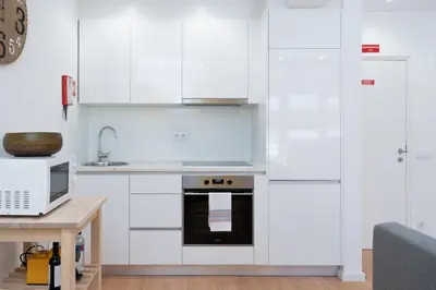 a white kitchen with white cabinets and a microwave at Host Wise - Sweet Sunny Flat with Balcony in Vila Nova de Gaia