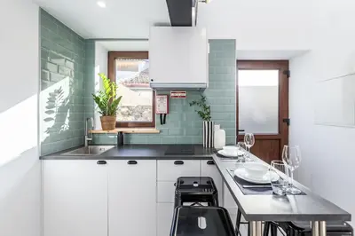 a kitchen with white cabinets and a table with chairs at Chic Loft with Garden, Sleeps 4 in Porto
