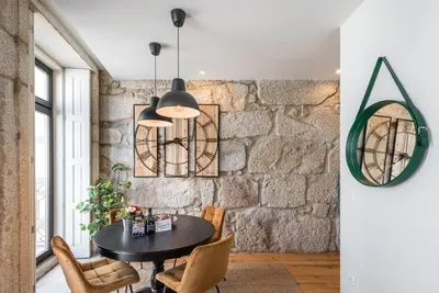a dining room with a stone wall and a table and chairs at GuestReady - Industrial stay in downtown Porto in Porto