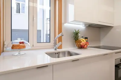 a white kitchen with a sink and a window at Host Wise - Elegant Home in the Heart of Porto in Porto