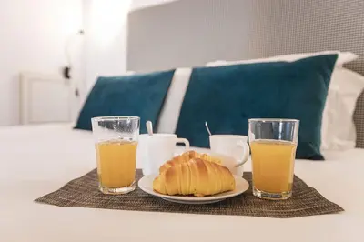 a table with a plate of food and two glasses of orange juice at Vila Terra Studio III in Vila Nova de Gaia