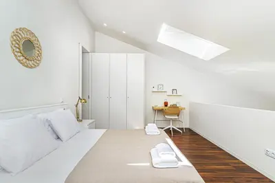 a white bedroom with a bed and a desk at Bombarda 250 by LovelyStay in Porto