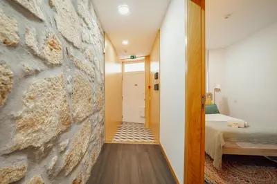 a hallway leading to a bedroom with a stone wall at Chillout Trindade Home by Vacationy in Porto