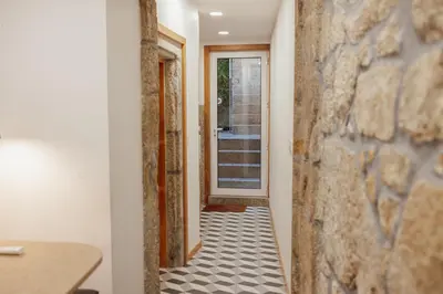 a hallway with a stone wall and a tile floor at Chillout Trindade Home by Vacationy in Porto