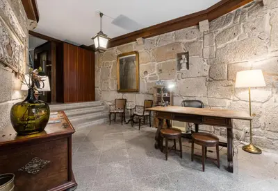 a room with a table and chairs and a stone wall at Office Suits in Flores by D&S in Porto