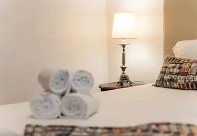a pile of towels on a bed with a lamp at Office Suits in Flores by D&S in Porto