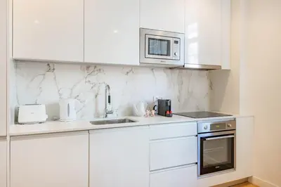 a white kitchen with a white table and stools at Paraíso City Stay I in Porto