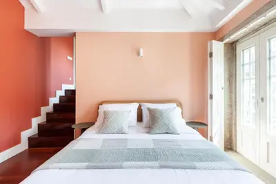 a bedroom with a bed with orange walls and a staircase at Superb Apartment in the HEART of Historical Center in Porto