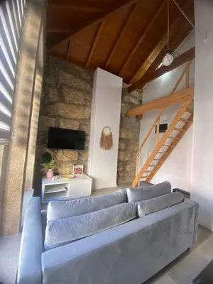 a living room with a blue couch in front of a stone wall at Porto Saldanha - 2x T2 Duplex in Porto